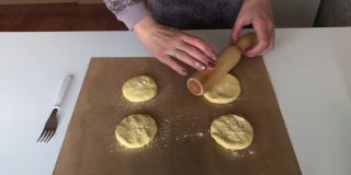 一个妇女用玉米面做无酵面包。把面团放在不粘的垫子上擀开。