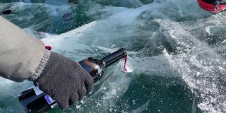 贝加尔湖之吻是游客的娱乐活动。一名男子将冰冻的贝加尔湖上的葡萄酒倒入临时搭建的玻璃杯中。