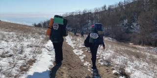 一群背着背包的游客沿着小路走向结冰的贝加尔湖。