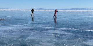 在贝加尔湖上滑冰。一个男孩和一个女孩拿着滑雪杖在结冰的贝加尔湖上滑冰。