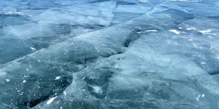 慢动作视频-一个人在贝加尔湖光滑透明的蓝色冰上打碎一块冰。
