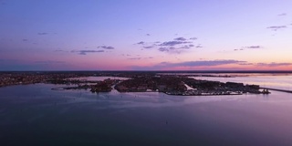 在夕阳下的大城市映衬下的紫色威尼斯泻湖