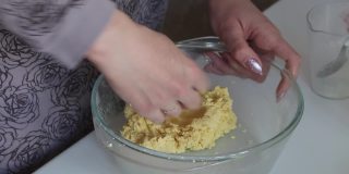 一个女人用玉米面做面团。用手混合面粉和水。使无酵饼。特写镜头从上面。