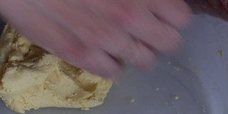 一个女人用玉米面做面团。用手混合面粉和水。使无酵饼。特写镜头从上面