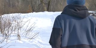 后视图跑步年轻的女孩穿着深色运动服慢跑在公园的树与雪的背景。健康的生活方式的概念。