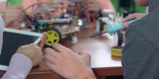 中学阶段:教师向孩子们讲解如何使用机器人程序，让孩子们饶有兴趣地学习。