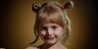 快乐的小女孩舔融化的巧克力，孩子吃，享受不健康的甜食室内