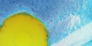 水晶发芽。蓝色背景上的抽象黄色斑点。抽象的垃圾艺术，墨水颜料扩散爆炸的背景。