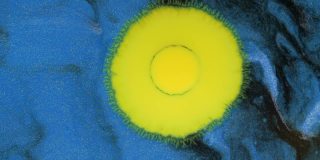 水晶发芽。抽象的黄色斑点在一个暗，蓝色的背景。抽象的垃圾艺术，墨水颜料扩散爆炸的背景。