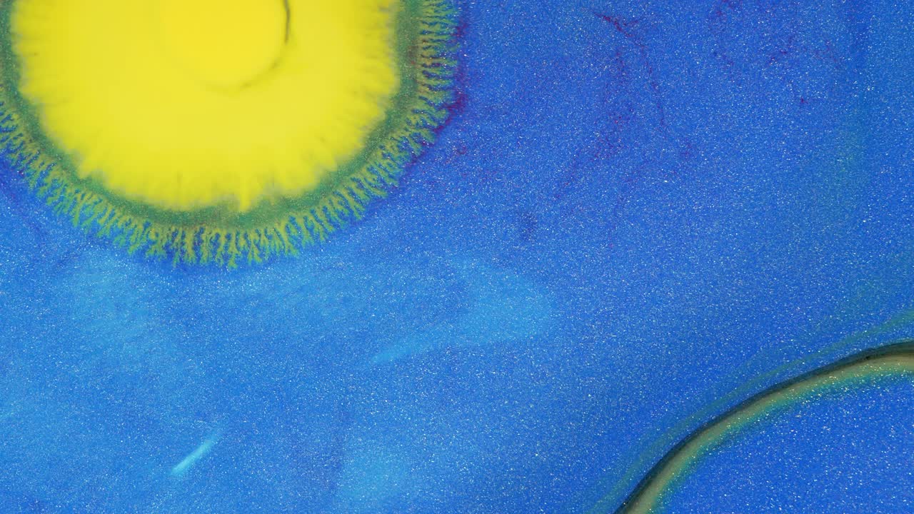 水晶发芽。蓝色背景上的抽象黄色斑点。抽象的垃圾艺术，墨水颜料扩散爆炸的背景。