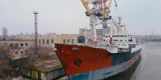 废弃的沉没锈迹斑斑的船多年停泊在港口，有多吨位起重机和商业建筑