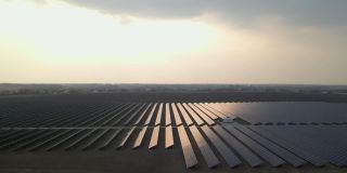 早春日落时分，无人机拍摄到太阳能农场的大型太阳能电池板。太阳能电池发电厂。录像视频4 k。