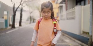 小日本女学生在住宅区樱花树下步行上学