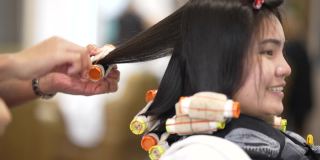 亚洲妇女在美容院，她卷头发和拉直头发。