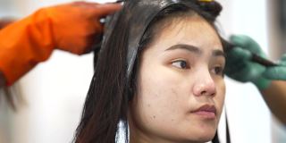 亚洲妇女在美容院，她卷头发和拉直头发。