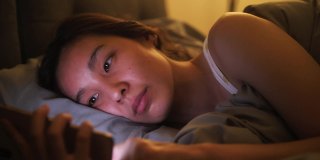 一个亚洲女人在床上玩手机