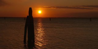 日落时分，黑暗的威尼斯泻湖的支柱水道标志