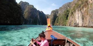 在泰国甲米省披披岛，一名亚洲女子坐在泰国的士船上，用智能手机拍摄安达曼海上的热带岛屿。适合旅游休闲。4 k慢动作。