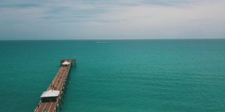 在朱诺海滩码头鸟瞰图，佛罗里达州与明亮的蓝色海水正午在春假期间在2021年3月