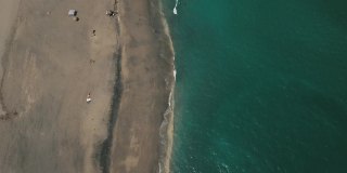 2021年3月春假和2019冠状病毒病期间，佛罗里达州朱诺海滩海滩海岸线上的一艘废弃帆船的动态鸟瞰图