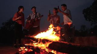 朋友们在野外露营时，在火边跳舞、弹吉他。视频素材模板下载