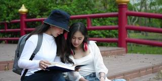 两个女大学生坐在校园里看书。