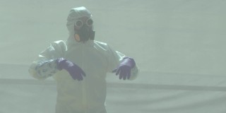 一名身穿白色化学防护服的男子摘下眼镜和防毒面具，倾身吐出厌恶的唾沫。在那之后，他走出了画框。在白色烟雾缭绕的房间里拍摄。