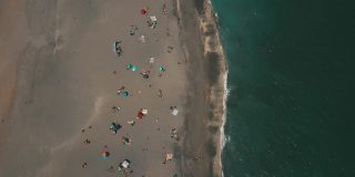 2021年3月春假和新冠肺炎期间，佛罗里达州朱诺海滩海滩海岸线上的彩色沙滩伞和人们的动态鸟瞰图