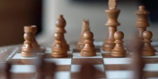 木制棋子后面的缓慢追踪射击。国际象棋游戏背景。摄像机沿着棋盘移动