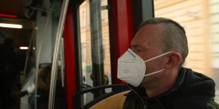男性乘客在城市乘坐公共交通工具时佩戴呼吸器。他等待释放。