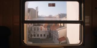 从运动中的火车窗口观看。旧城的都市化。阳光。