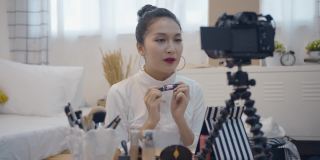 年轻的亚洲女性美网博主录制视频与化妆品