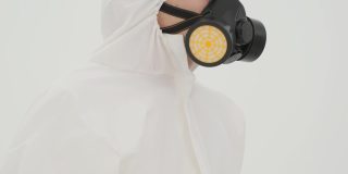 特写的人在防护服脱下防毒面具从自己。在白色背景上拍摄。