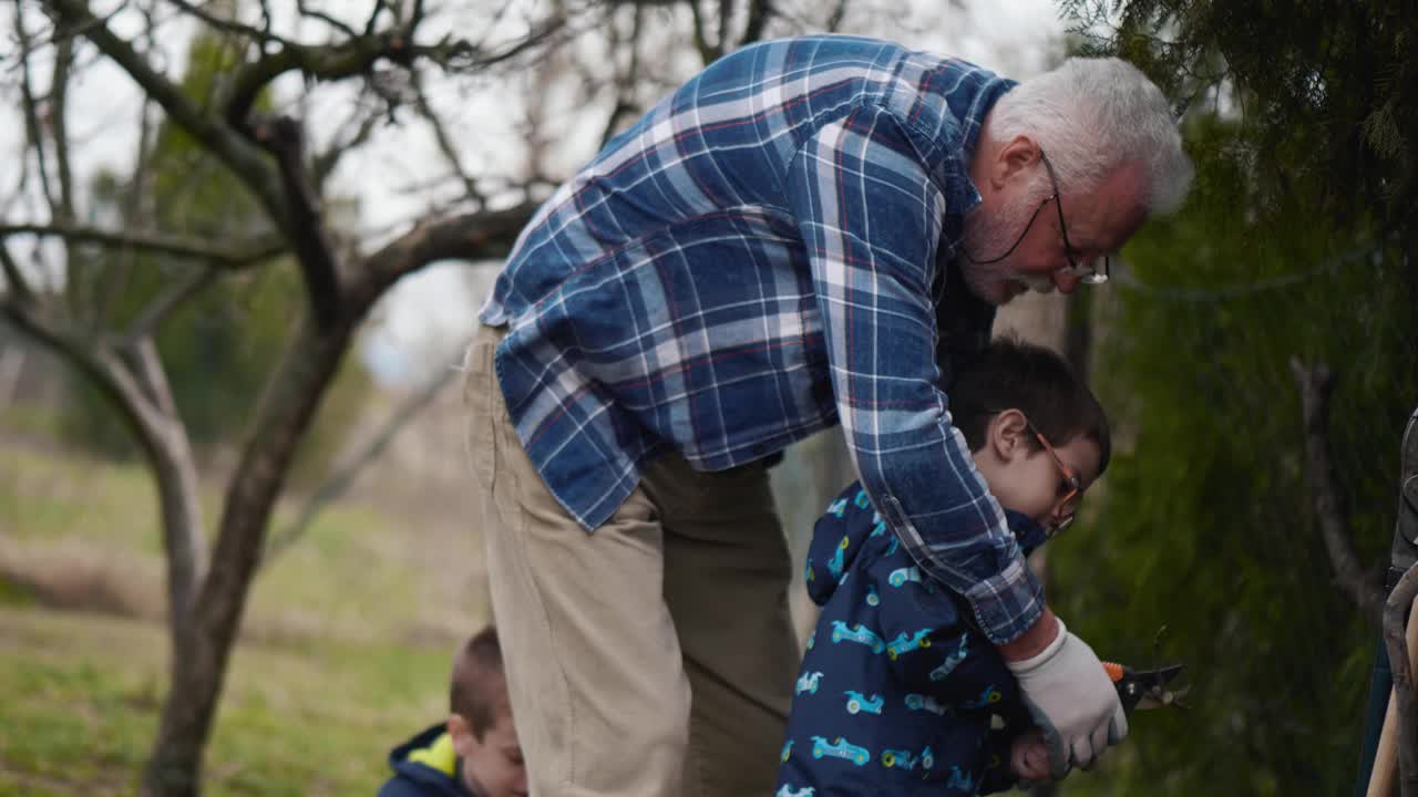一位长者教一个小男孩如何种葡萄。爷爷和孙子在花园里干活