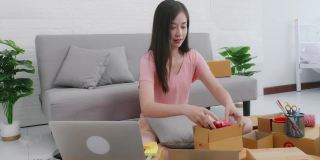 女亚洲企业家包装邮船箱为客户准备快递包裹