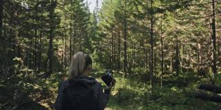 游客在森林中拍摄风景。一名白人女性拍摄了漂亮的魔术。女孩用无反光镜单反相机拍摄视频。