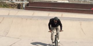 一个年轻的黑人男子在滑板公园与小轮车跳跃的慢动作。城市运动