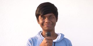 一个印度孩子的肖像拿着黑色的麦克风在白色的背景和对着镜头微笑