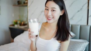 喝牛奶的亚洲年轻女子。早上下班之前。视频素材模板下载