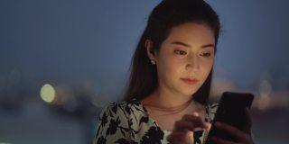 CU:迷人的亚洲女人在晚上使用手机。