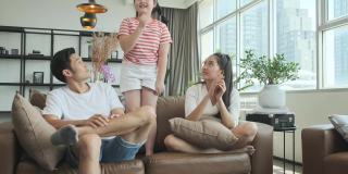 快乐快乐亚洲可爱的家庭享受看电视和唱歌跳舞一起在沙发上练习，有趣和欢乐的周末活动在电视机前的客厅
