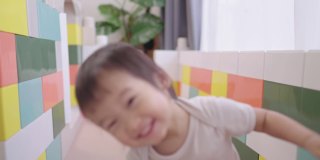 肖像可爱的露齿微笑的小女孩独自在一个大玩具屋里玩，亚洲迷人的小深褐色眼睛蹒跚学步的孩子靠近和微笑在前面的焦点，自信的童年
