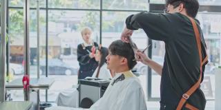 亚洲专业发型师团队为年轻客户提供美容院服务和治疗。专业造型师在美容院或理发店为男性和女性梳头、剪头发