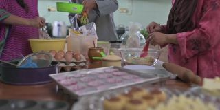 马来西亚马来人兄弟姐妹成年子女帮助母亲在厨房烘焙准备家庭在家里庆祝开斋节