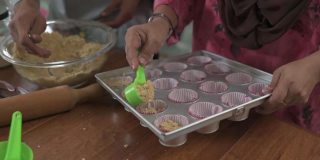 上角马来西亚马来人的兄弟姐妹成年子女帮助母亲在厨房烘焙准备家庭庆祝开斋节