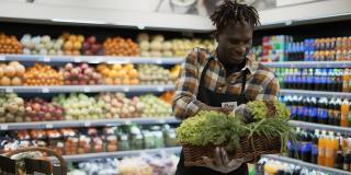 非裔美国人微笑的工人在超市安排绿色蔬菜