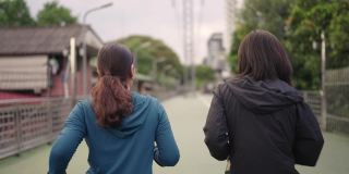 两个亚洲女运动员一起跑在公园，后视镜，慢镜头