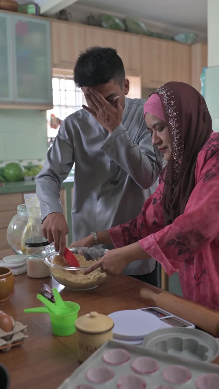 马来西亚马来人儿子成年子女帮助母亲在厨房烘焙准备家庭在家里庆祝开斋节