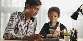 亚洲父亲解释家庭作业，帮助孩子在数字平板电脑