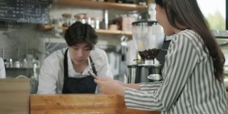 咖啡师在咖啡店为商务女性顾客提供咖啡杯。